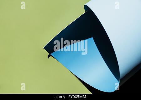 Papier bleu gondolé créant des ombres sur fond vert. Banque D'Images