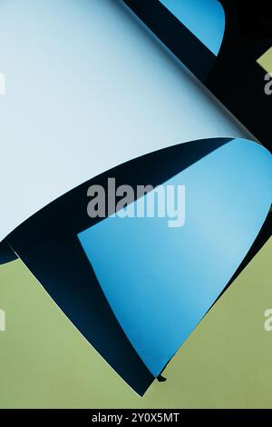 Papier bleu gondolé créant des ombres sur fond vert. Banque D'Images