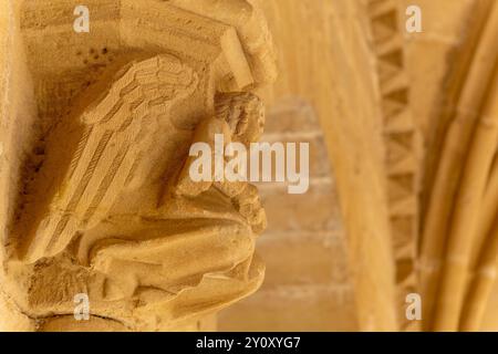 Une statue d'un ange agenouillé avec ses mains sur ses genoux. La statue est en pierre et est située sur un bâtiment. Architecture médiévale. Détail de Banque D'Images
