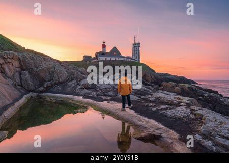 Phare de Saint-Mathieu au lever du soleil, avec un homme debout sur la falaise, sur la pointe Saint-Mathieu à Plougonvelin, Brest, France Banque D'Images