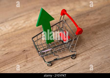 Un panier miniature avec une grande flèche verte vers le haut. Croissance économique, augmentation des dépenses de consommation, montée du concept de commerce électronique. Banque D'Images