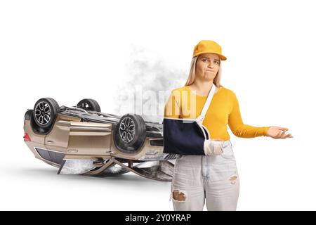 Jeune femme blessée avec un bras cassé portant une attelle de bras devant un accident de voiture isolé sur fond blanc Banque D'Images