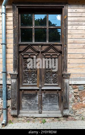 Une porte en bois magnifiquement sculptée se dresse à une vieille structure sous un ciel bleu clair. Banque D'Images