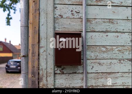 Une simple boîte aux lettres brune est montée sur un mur en bois rustique dans un quartier résidentiel serein. Banque D'Images