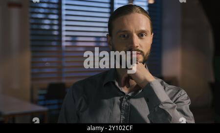 Homme d'affaires caucasien pensive penser le travail de bureau du soir regardant la caméra portrait homme d'affaires entrepreneur chef de la direction de l'entreprise employeur Banque D'Images