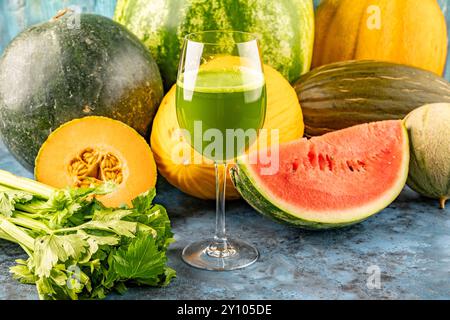 Pastèque et melon boire du jus frais dans le verre. La boisson est sur un fond bleu avec une demi-pastèque, melon et céleri en arrière-plan Banque D'Images