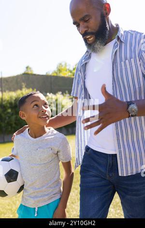 Grand-père et petit-fils se liaient, tenant un ballon de football et parlant à l'extérieur Banque D'Images