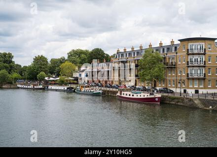 Vue sur la rive de Windsor de la Tamise vers le restaurant Boatman et les barges amarrées et les péniches étroites. Windsor Berkshire Angleterre Royaume-Uni Banque D'Images