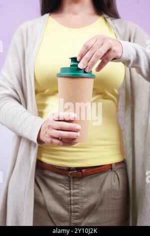 Femme méconnaissable tient une tasse réutilisable avec un couvercle vert. Banque D'Images