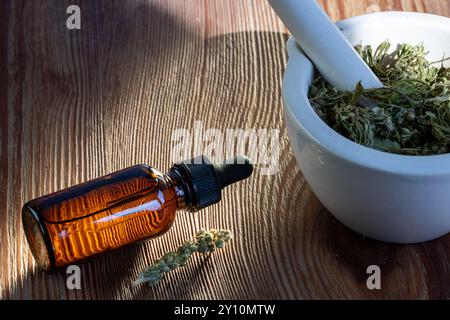 Bouteille compte-gouttes en verre ambré et mortier avec herbes séchées Banque D'Images