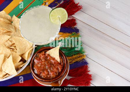 Vue en haut angle d'un cocktail de margarita avec frites et salsa sur une table en bois rustique blanc. Format horizontal avec espace de copie. Banque D'Images