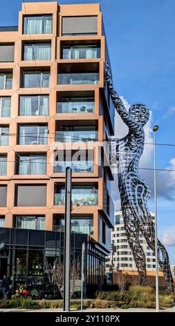 Amsterdam, pays-Bas - 15 mars 2024 : complexe d'appartements moderne avec façade géométrique et grande sculpture métallique de figure humaine, mettant en valeur innovati Banque D'Images