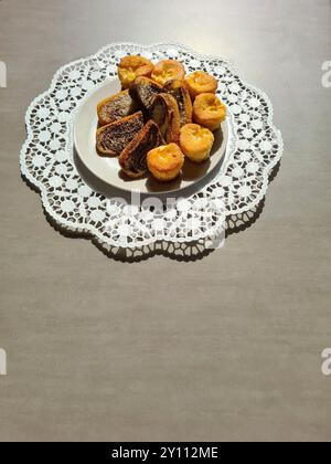 Morceaux individuels de gâteau de marbre et muffins servis sur une assiette blanche sur un dessus de gâteau en papier décoratif rond sur un fond gris Banque D'Images
