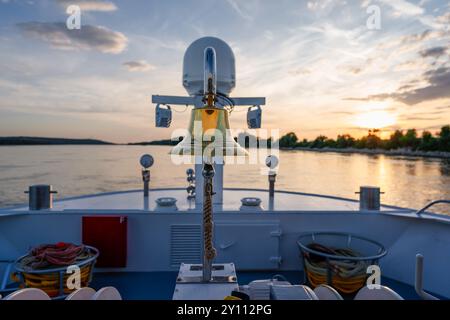 bateau de croisière au coucher du soleil, balustrade chromée sur le pont de soleil, sur la rivière avec de l'eau, forêt, rive dans le delta du danube en roumanie, romantique avec le ciel bleu, heure bleue Banque D'Images