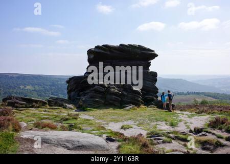 Hathersage Moor, Derbyshire, Royaume-Uni, août 31, 2024 : deux randonneurs se tiennent près d'une grande formation rocheuse Mothers Cap, par une journée ensoleillée dans un paysage pittoresque. Banque D'Images