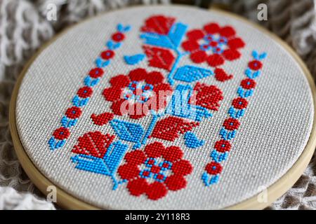 Broderie ukrainienne, 'vyshyvka', de l'est de l'Ukraine où les fleurs bleues et rouges dominent sur les motifs géométriques traditionnels noir et rouge. Banque D'Images