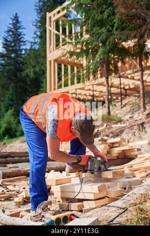 Menuisier utilisant une scie circulaire pour couper des planches de bois. Homme ouvrier construisant une maison à ossature en bois. Concept de pratiques de construction contemporaines et écologiques. Banque D'Images