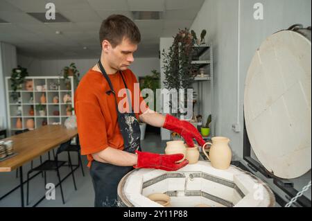 Homme caucasien chargeant des produits en céramique dans un four spécial. Banque D'Images