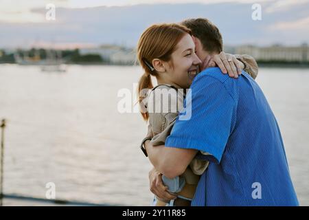 Couple embrassant près du paysage du front de mer pendant le coucher du soleil Banque D'Images