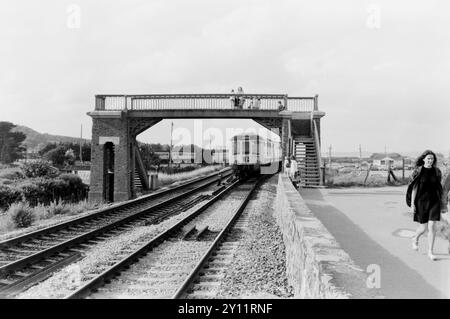 British Rail Class 119 DMU numéro P586 construit par Gloucester Railway Carriage & Wagon Co. Ltd passant sous Dawlish Warren Footbridge, Iron Footbridge, S W Coast Path, Dawlish Warren, Devon, Royaume-Uni, en été 1972. Brunel Holiday Park voitures de chemin de fer au-delà. Paignton embarque à bord du train Banque D'Images