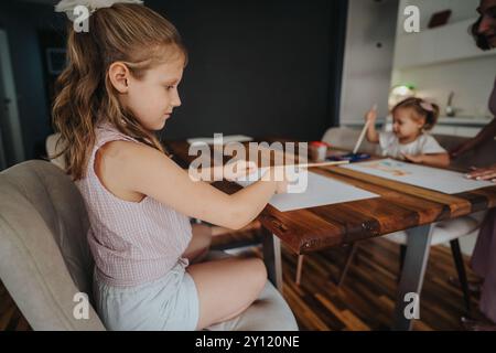 Mère avec filles s'engageant dans une activité de peinture amusante et créative à la maison Banque D'Images