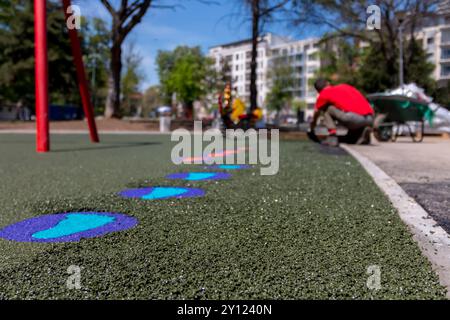 Nouvelle aire de jeux pour enfants en construction. Une main maçon avec étalement de truelle et nivellement de miettes de caoutchouc souple paillis en caoutchouc pour playgrou pour enfants Banque D'Images