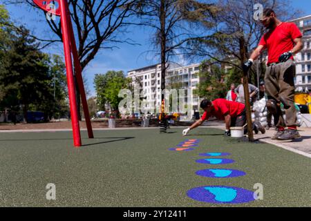 Nouvelle aire de jeux pour enfants en construction. Une main maçon avec étalement de truelle et nivellement de miettes de caoutchouc souple paillis en caoutchouc pour playgrou pour enfants Banque D'Images