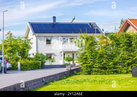 Charmante villa blanche de deux étages avec panneaux solaires et drapeau suédois, nichée dans un quartier résidentiel verdoyant. Suède. Banque D'Images