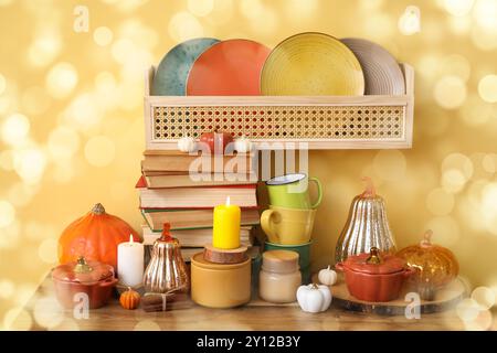 Différents plats, décor d'automne et livres sur une table en bois près du mur jaune Banque D'Images