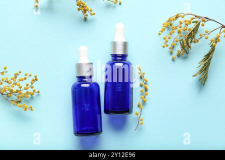 Composition avec des bouteilles d'huile essentielle et des fleurs de mimosa sur fond de couleur Banque D'Images