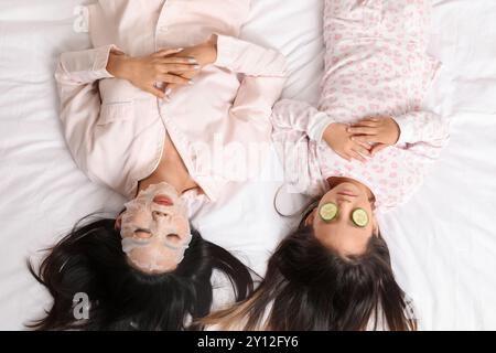 Mère asiatique avec sa petite fille se relaxant sur le lit, vue de dessus Banque D'Images