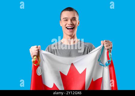 Joyeux nageur masculin avec drapeau du Canada et médaille de la première place sur fond bleu Banque D'Images