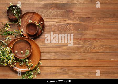 Composition avec différentes assiettes et fleurs de camomille fraîches sur fond en bois Banque D'Images