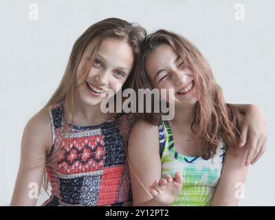 portrait de deux petites filles heureuses riant et goofing autour sur le fond clair Banque D'Images