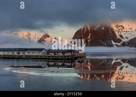 Maisons norvégiennes typiques dans le fjord en face de montagnes escarpées, brouillard marin, hiver, Reine, Moskenesoya, Lofoten, Norvège, Europe Banque D'Images