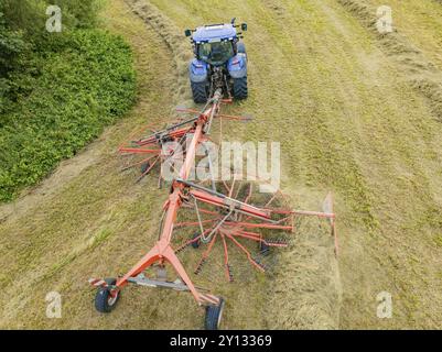 Vue aérienne d'un tracteur avec machine à foin dans un champ, entouré d'herbe coupée et de balles de foin, Dachtel. Forêt Noire, Allemagne, Europe Banque D'Images