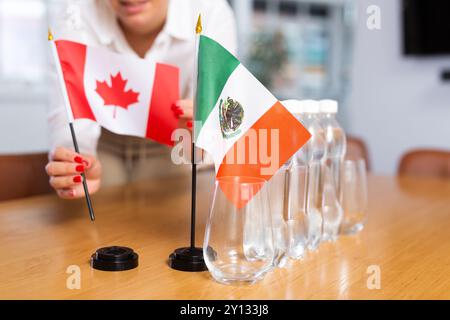 Fille méconnaissable pose des drapeaux midget du Mexique et du Canada avant les négociations internationales Banque D'Images