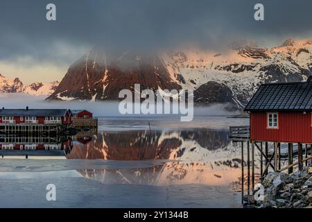 Maisons norvégiennes typiques dans le fjord en face de montagnes escarpées, brouillard marin, hiver, Reine, Moskenesoya, Lofoten, Norvège, Europe Banque D'Images