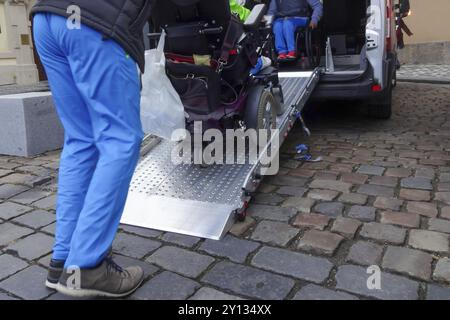 Aide Assistant personne handicapée sur fauteuil roulant avec l'aide de transport accessible van ramp Banque D'Images