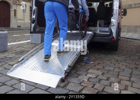 Aide Assistant personne handicapée sur fauteuil roulant avec l'aide de transport accessible van ramp Banque D'Images