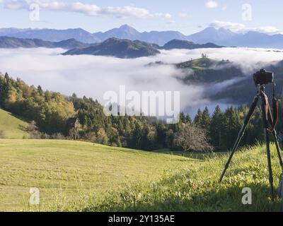 Beau paysage de lever de soleil de l'église Saint Thomas en Slovénie sur une colline dans le brouillard du matin et le fond de montagne Triglav Banque D'Images