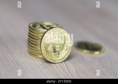 Pile de bitcoins à fond d'or avec une seule pièce faisant face à la caméra dans une mise au point avec l'ombrage sur l'icône lettre B sur la face de la peu co Banque D'Images