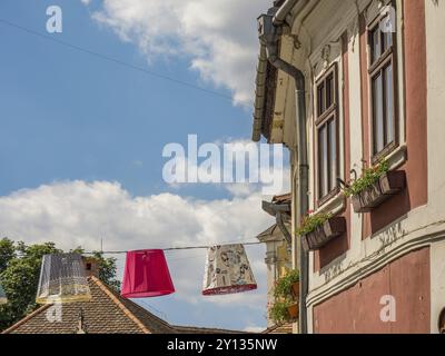 Abat-jours colorés suspendus au-dessus d'une ruelle dans un village aux fenêtres décorées et ciel partiellement nuageux, szentendere, Danube, Hongrie, Europe Banque D'Images