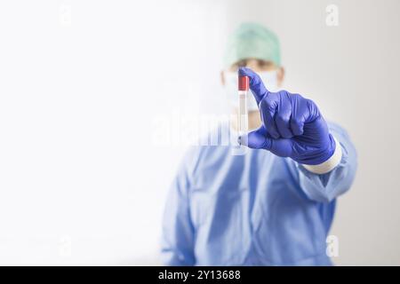 Médecin Chirurgien dans gants stériles à ampoule au tube à essai. Il porte la robe bleue et chirurgicale Banque D'Images