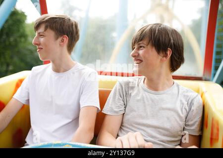 Deux amis profitant d'une promenade palpitante dans le parc d'attractions ensemble par une journée ensoleillée, remplie d'excitation et de rire Banque D'Images