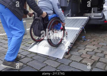 Aide Assistant personne handicapée sur fauteuil roulant avec l'aide de transport accessible van ramp Banque D'Images