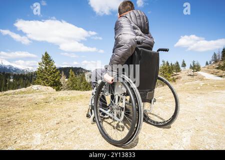 Jeune homme handicapé en fauteuil roulant à l'extérieur dans la nature l'observation de montagne et la nature Banque D'Images