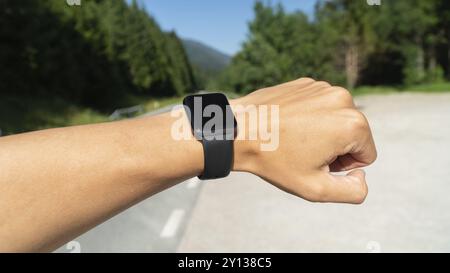 Coureur sur un sentier de montagne regardant une montre intelligente ou sportive, vérifiant la carte de position de navigation gps ou le tracé de pouls de fréquence cardiaque, à l'aide du moniteur cardiaque equ Banque D'Images