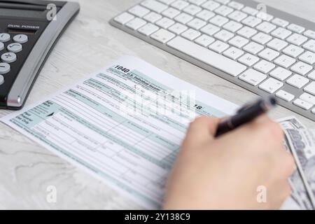 Point de vue, la photo d'une femme le calcul et le remplissage-nous Formulaire d'impôt suivant pour clavier de l'ordinateur et l'impôt sur le formulaire 1040. 15 avril 2019 Journée de l'impôt Banque D'Images