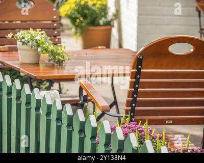 Table et chaises en bois dans le jardin avec des fleurs colorées, spiekeroog, frise orientale, mer du Nord, allemagne Banque D'Images